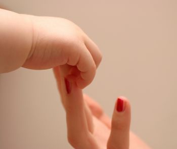 Mother and child hold hands in this touching image showing the loving gift that is the bond between a mom and her baby